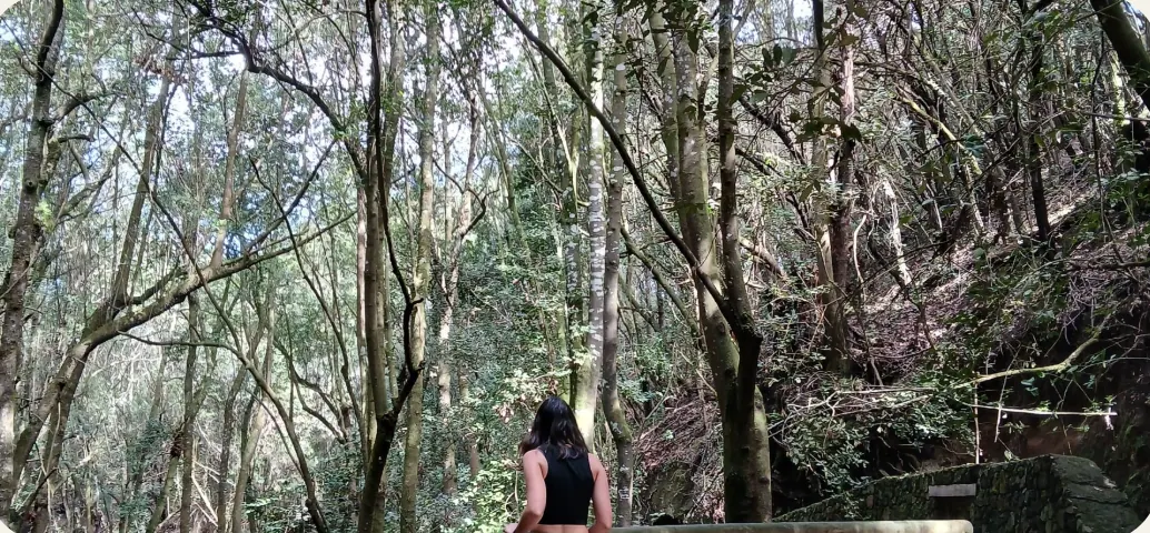Icíar de espaldas, apoyada en una barandilla de madera frente a un bosque